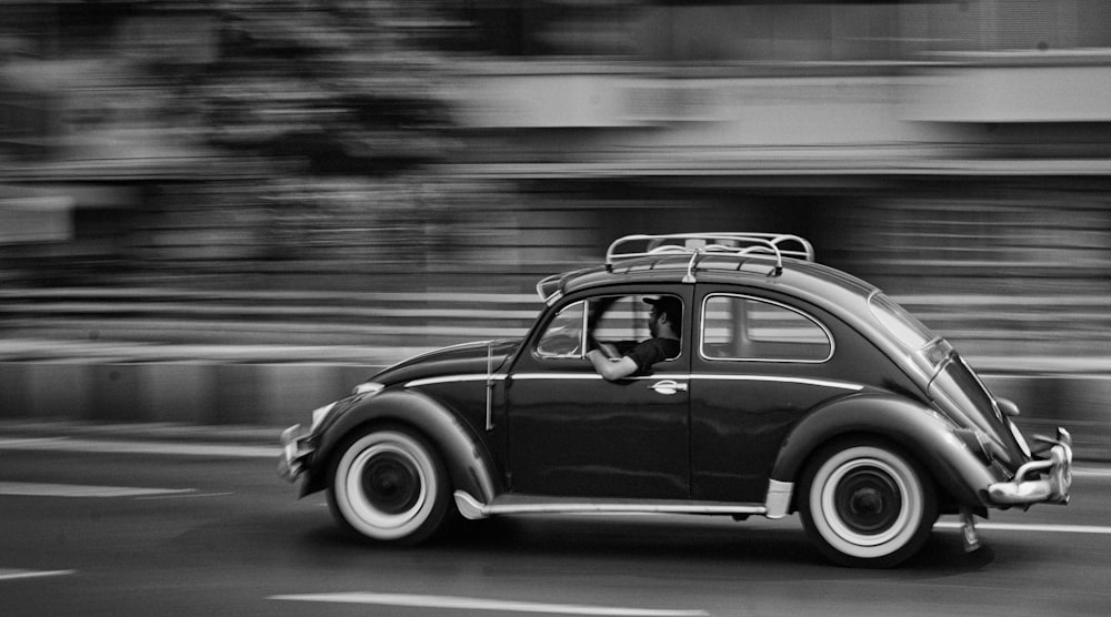 Photo en niveaux de gris d’une voiture de coccinelle en mouvement