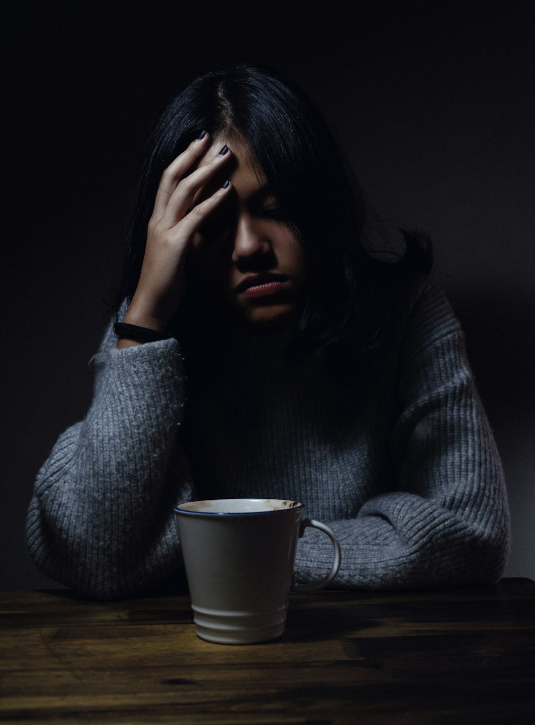 Woman with headache and cup of coffee