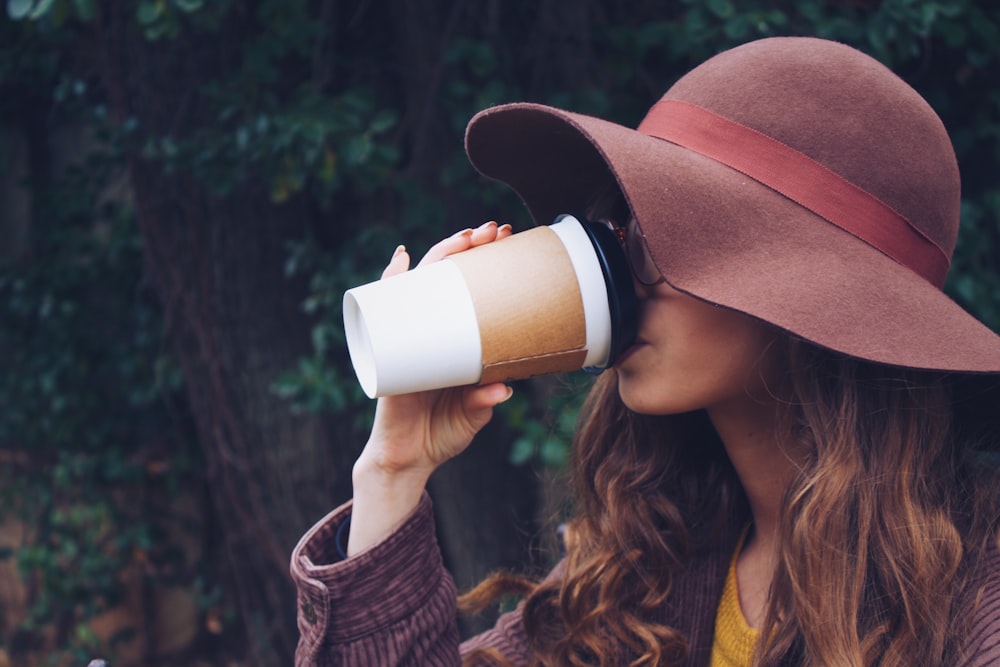 woman wearing brown hat drinking coffee