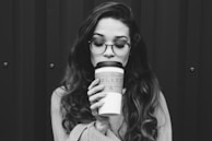 grayscale photography of woman holding disposable cup