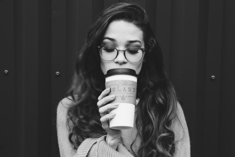 grayscale photography of woman holding disposable cup