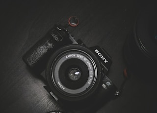 flat lay photography of black Sony DSLR camera on black surface