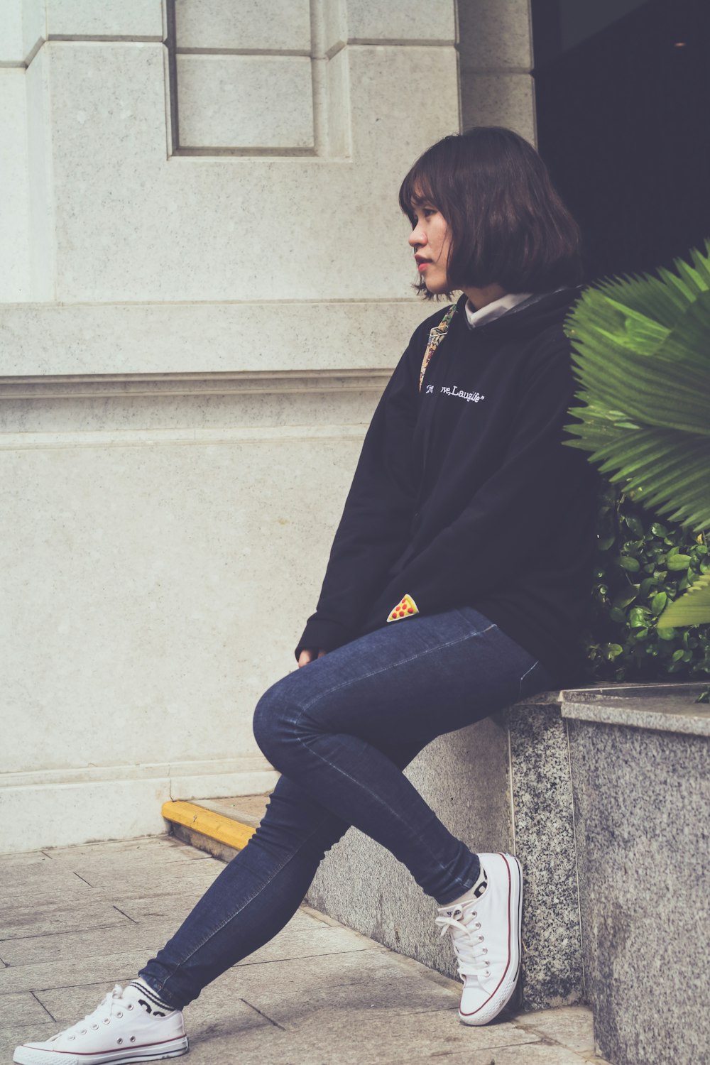 woman sitting on grey concrete pavement
