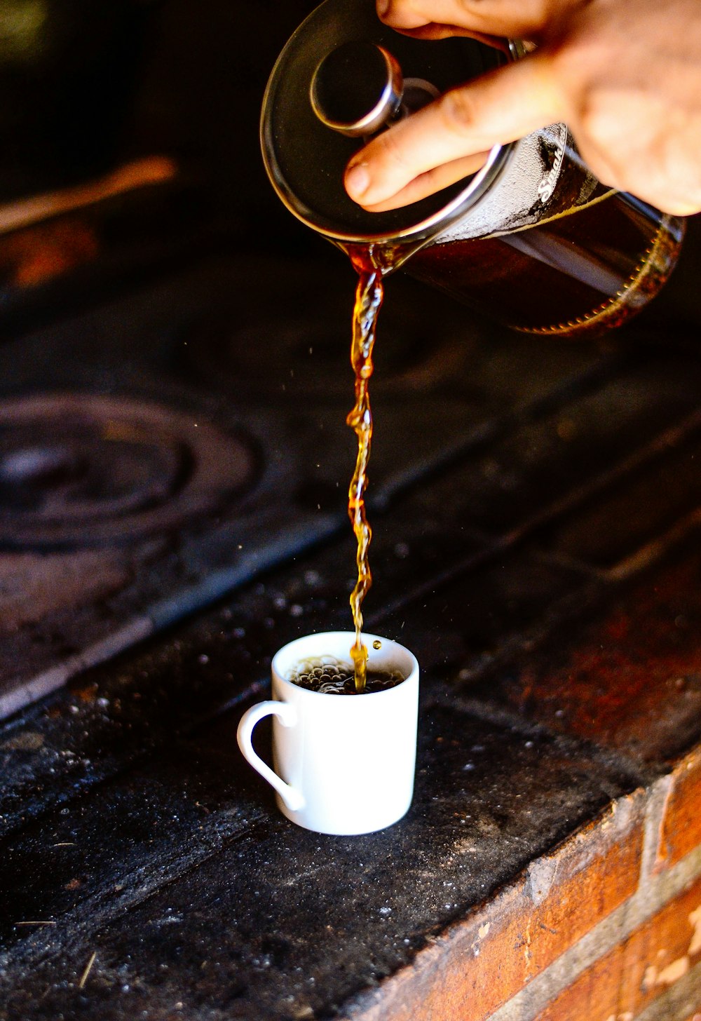 Person, die Kaffee auf weiße Keramik-Teetasse gießt