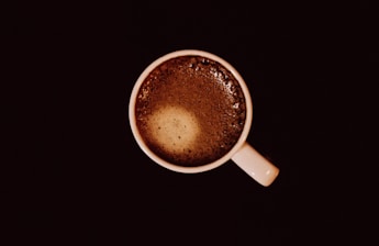 top view of white ceramic mug with brown liquid