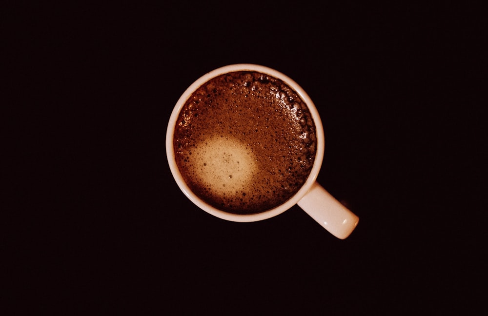 top view of white ceramic mug with brown liquid