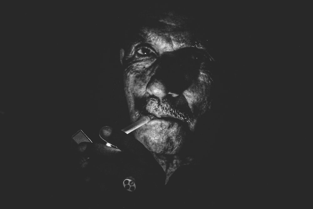 foto em escala de cinza do homem acendendo cigarro foto close-up