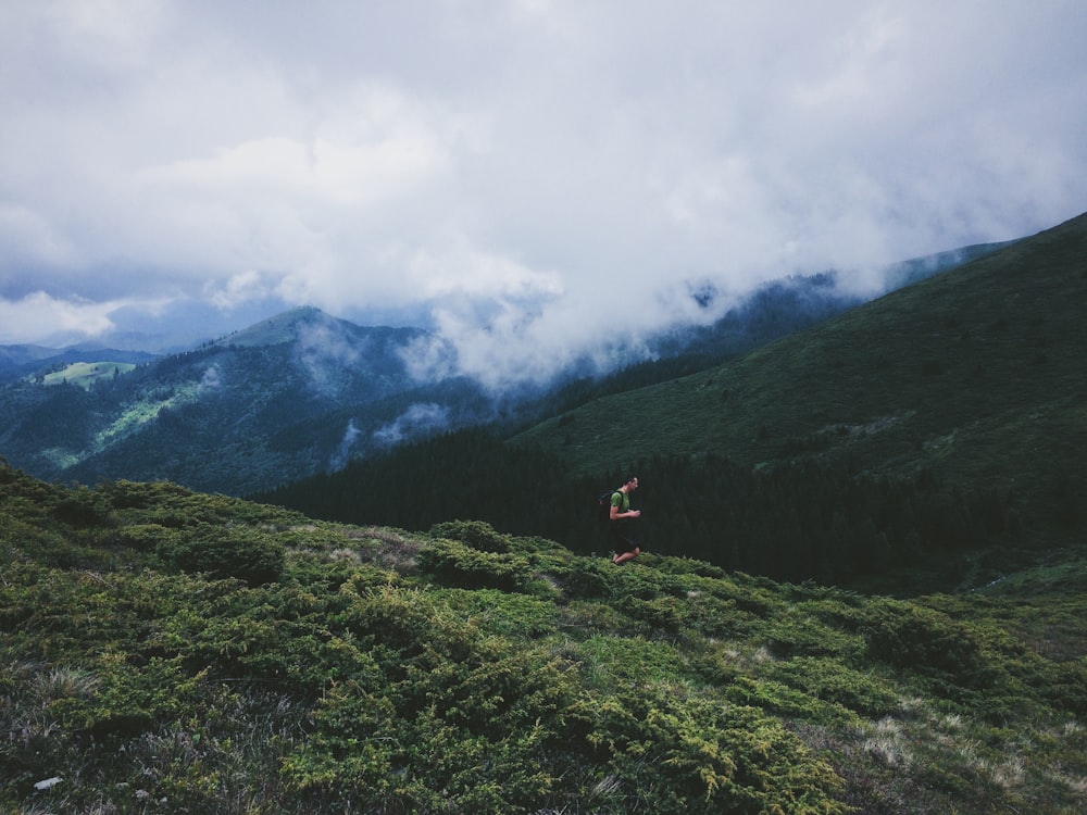 person walking on grass field near mountain