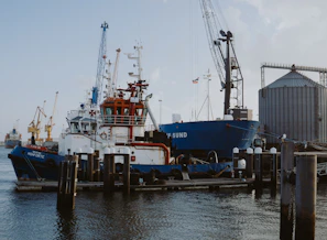 A fleet of ships docked at a harbor with clear branding of PT. Primaera Mandiri Perkasa on equipment.