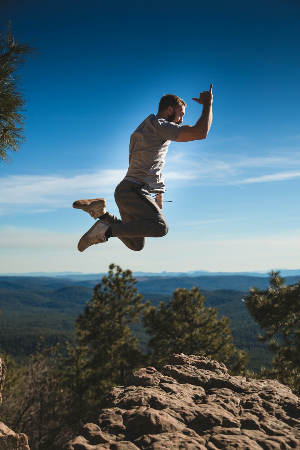 man jumping on brown rock formation