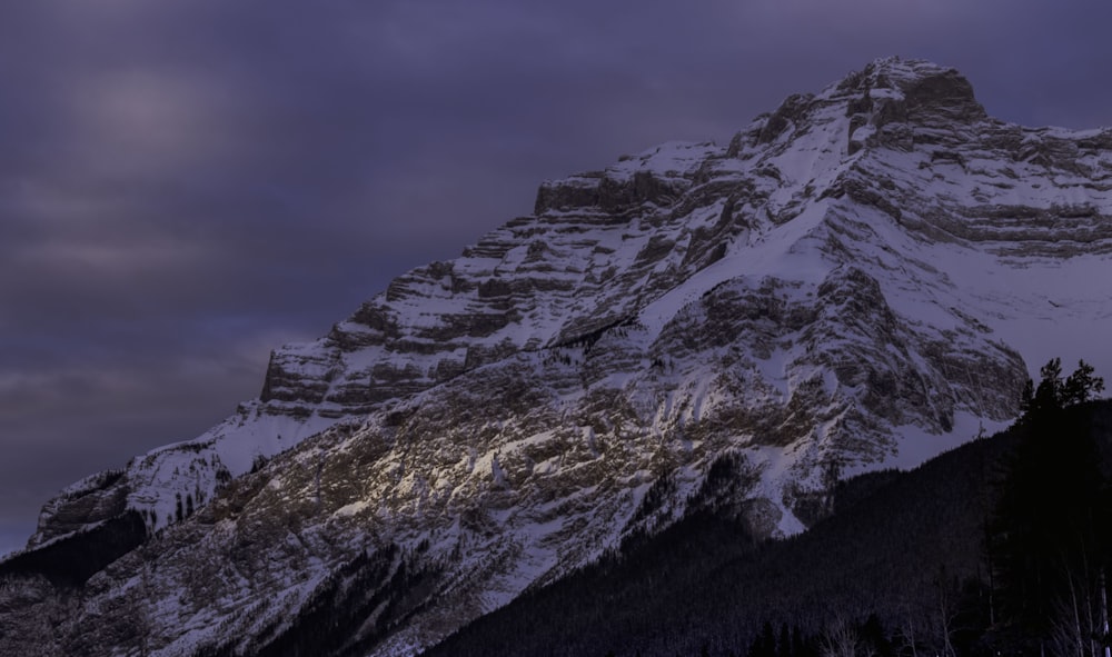 rock mountain covered with snow at daytime