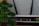 A close-up view of a Wi-Fi router with various indicator lights lit up, showing connectivity status. To the left, the blurred image of a decorative object, resembling a green Christmas tree, is partially visible.