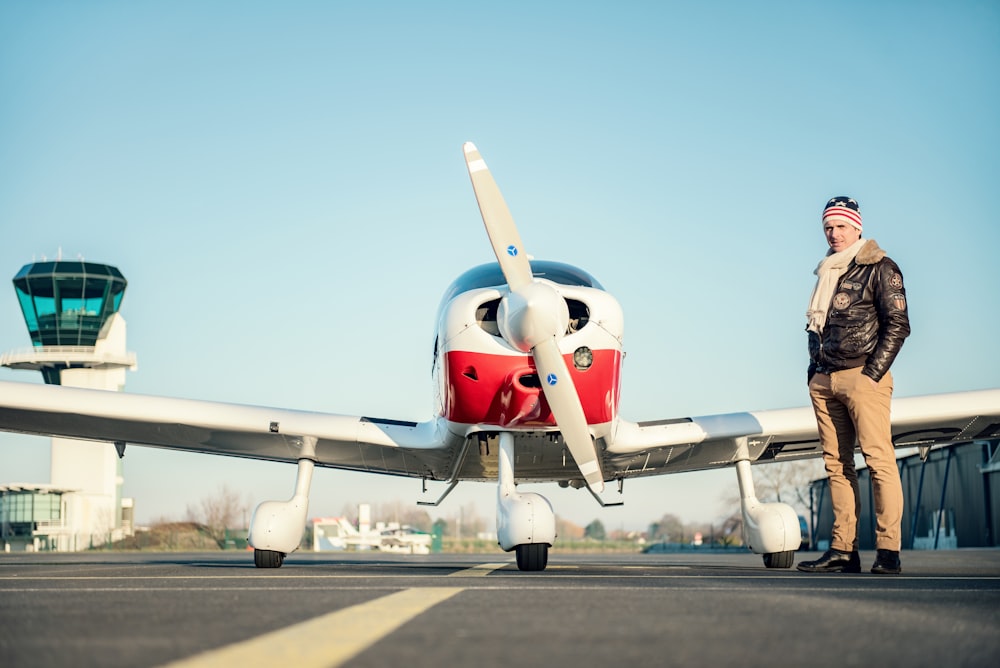 man standing near red biplane