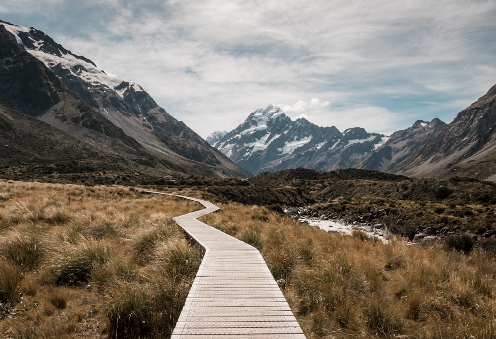 Muelle de madera marrón hacia la montaña cerca del arroyo y las montañas glaciares