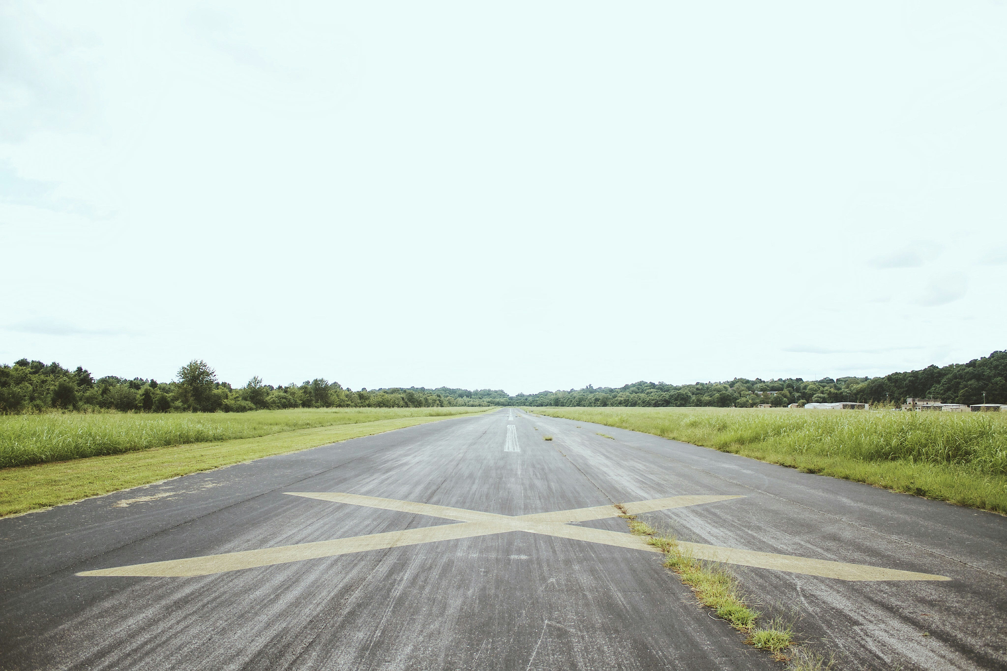 gray road surrounded by green grass during daytime, 