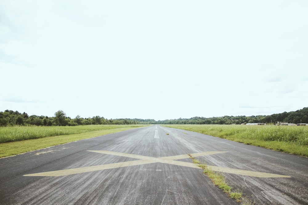 gray road surrounded by green grass during daytime