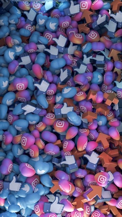 A dense pile of colorful 3D icons featuring popular social media logos such as Instagram, Twitter, and Facebook. The icons are intermingled and scattered across the frame, representing social media interaction symbols like hearts, thumbs-up, and upvotes.