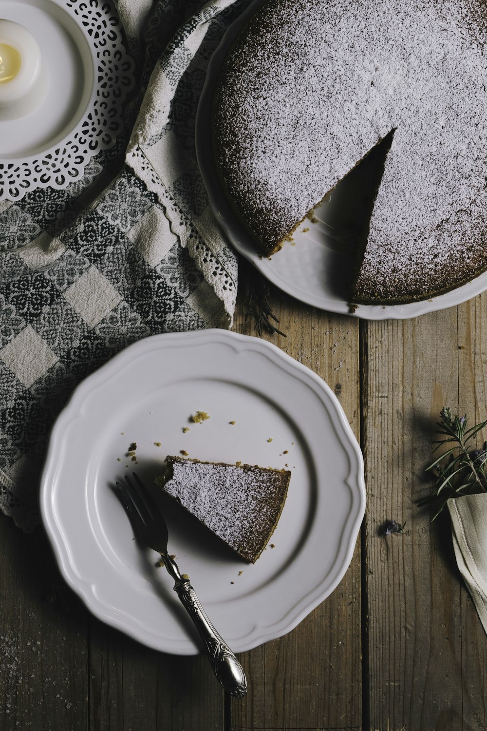 갈색 테이블에 얇게 썬 케이크와 포크가 있는 둥근 흰색 세라믹 접시
