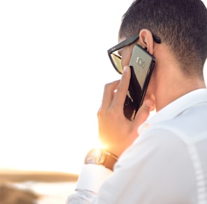 man holding smartphone standing in front of calm body of water