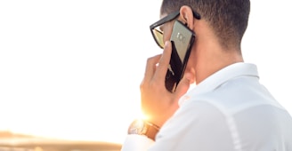 man holding smartphone standing in front of calm body of water