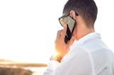 man holding smartphone standing in front of calm body of water