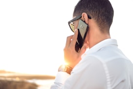 man holding smartphone standing in front of calm body of water