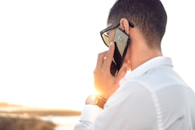 man holding smartphone standing in front of calm body of water