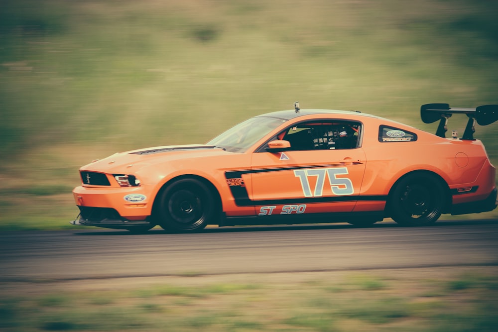 panning photography of orange racing car on road