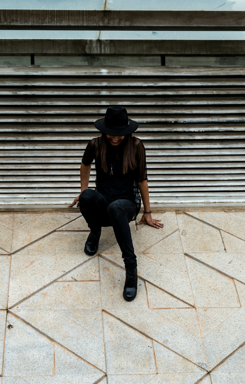 Frau im schwarzen Hemd sitzt auf grauem Beton