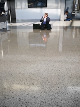 A business traveler confidently speaking into a sleek device at an airport lounge, with glowing amber accents highlighting the technology.