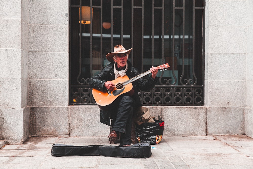 man sitting on chair playing guitar