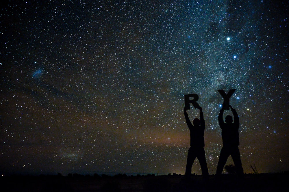 silhouette of two person holding letters R and Y under starry sky
