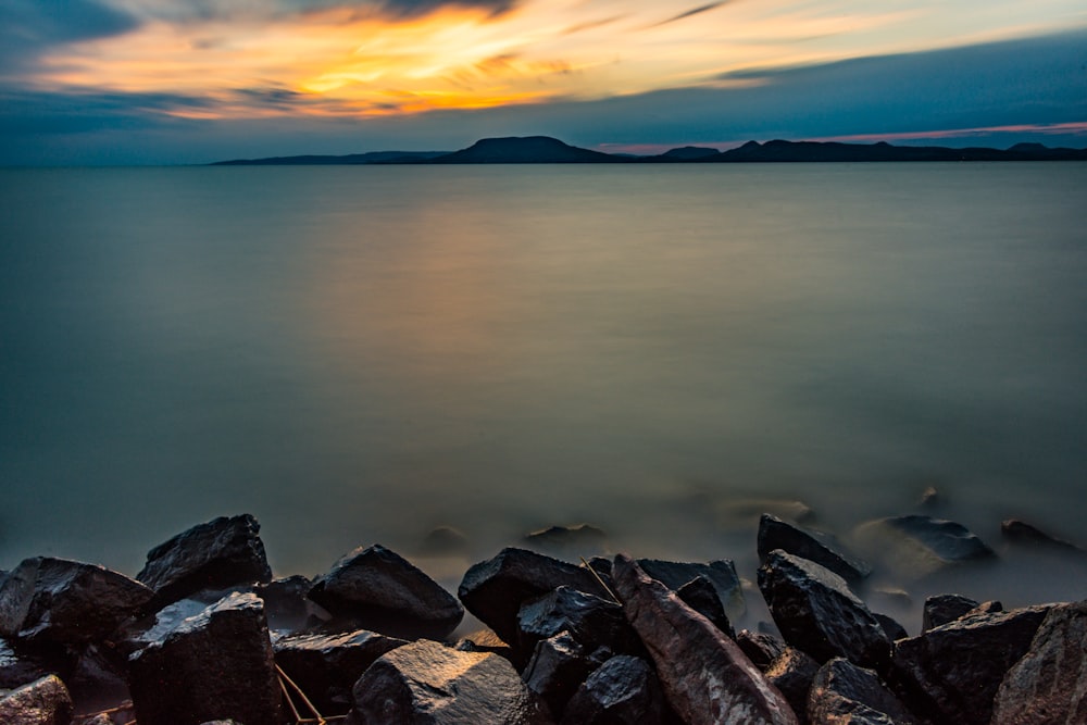 body of water under orange sunset