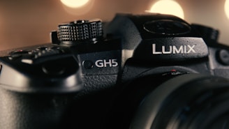Close-up view of a Panasonic Lumix GH5 camera with detailed focus on the logo and dials, illuminated by soft, warm lighting.