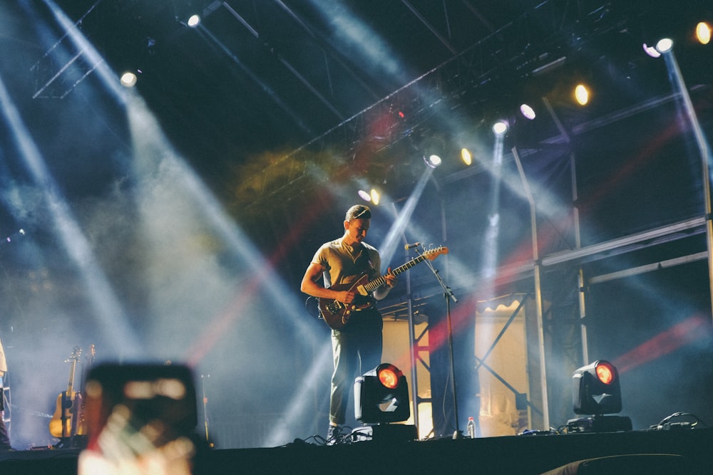 Mann spielt nachts Gitarre auf der Bühne