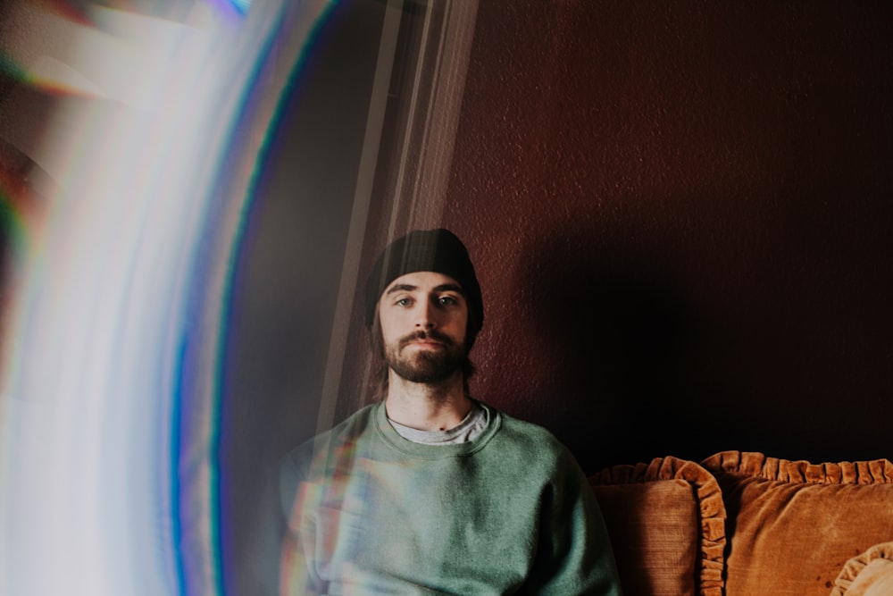 man sitting on brown sofa on front of brown wall