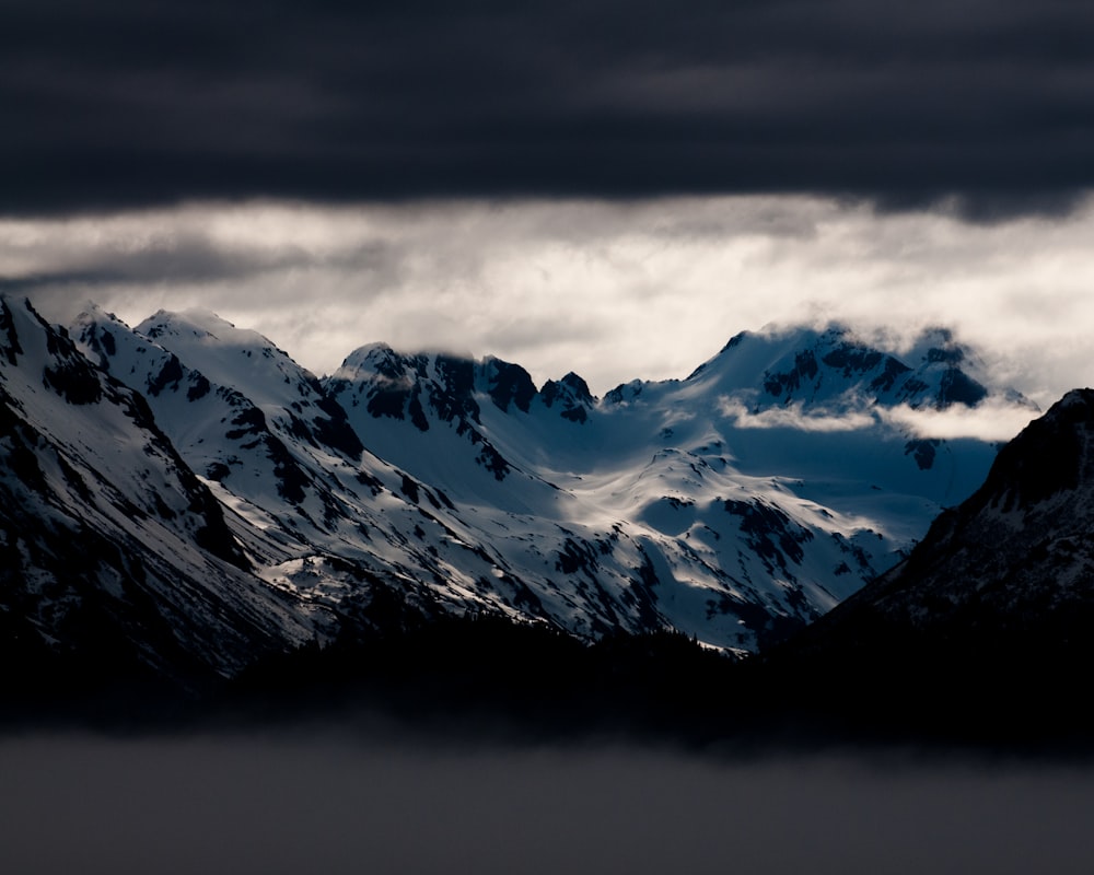 snow covered mountains under white clouds at daytime