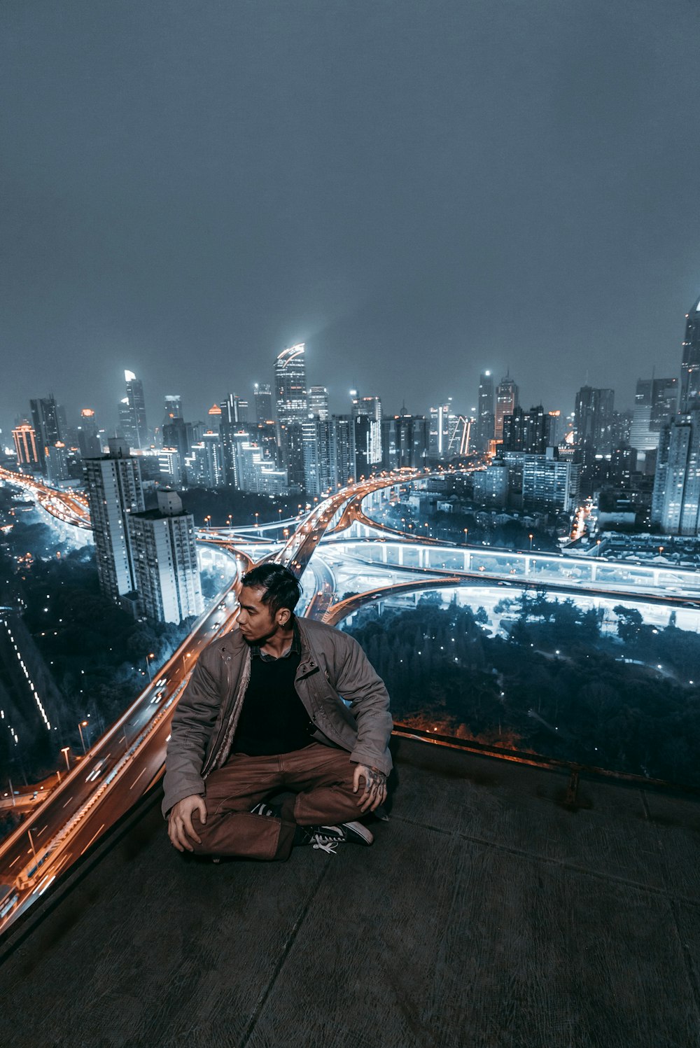 man sitting on rooftop looking his right side during night time