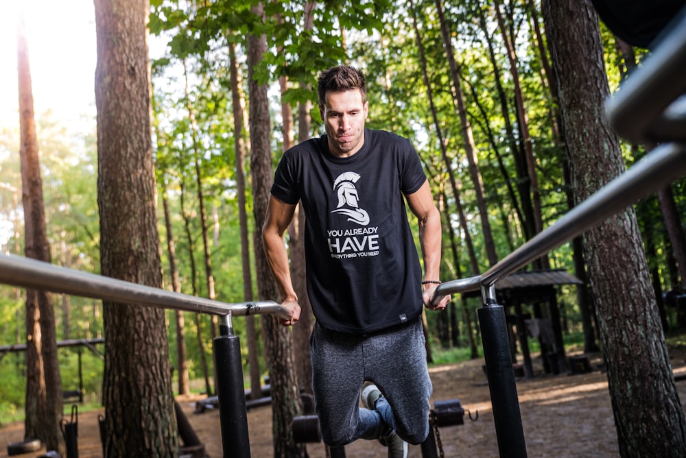 person doing dips on gray rails under shade of trees during daytime