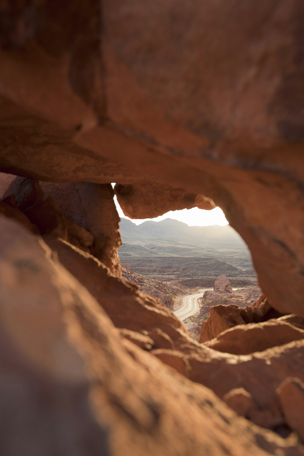 force perspective photography of brown rock cave overlooking highway at daytime