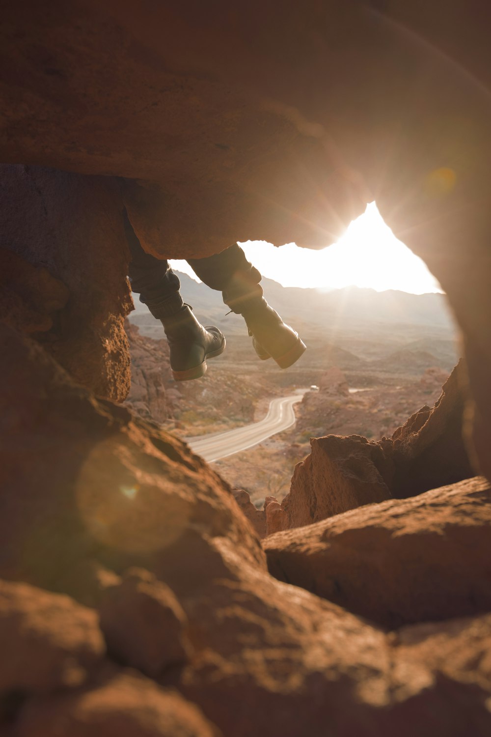 person sitting on brown monolith in golden hour background