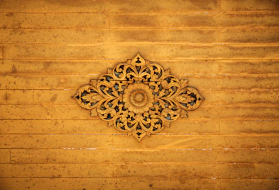 Close-up of a delicate laser-cut wooden panel with intricate floral patterns, softly lit to highlight the fine details.