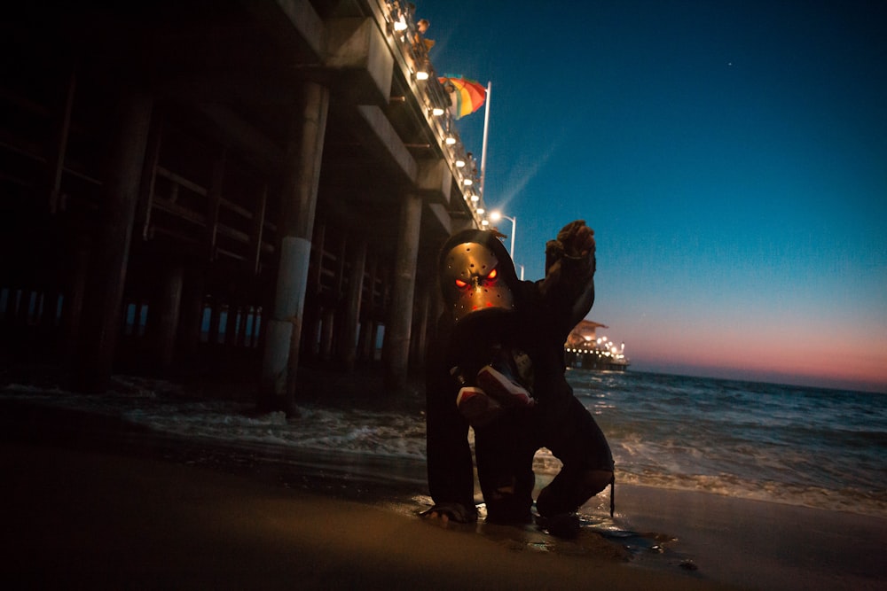 man kneeling on seashore digital wallpaper