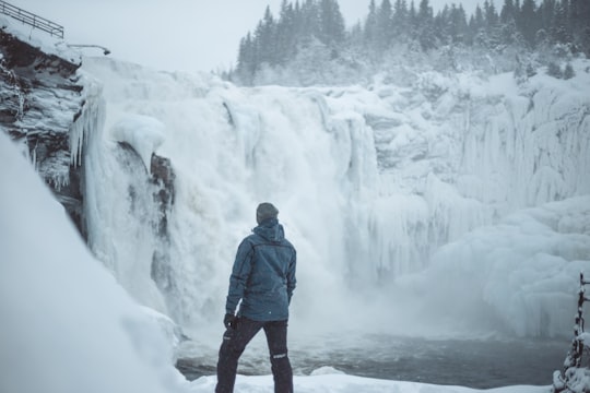 man standing near snow covered falls during daytime in Åre Sweden