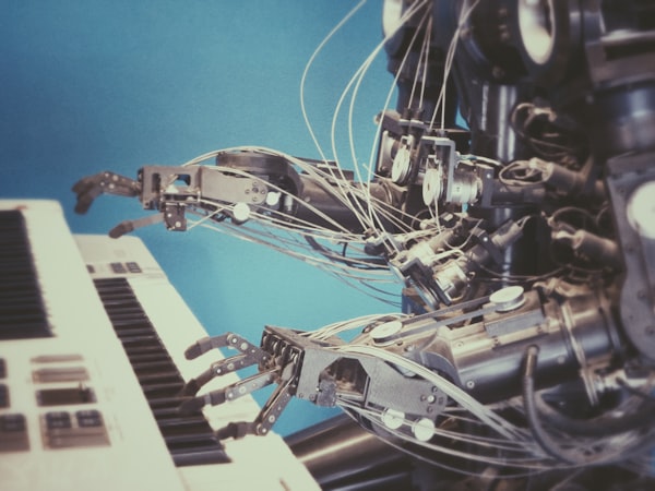a robot, its parts and wiring exposed, playing a keyboard