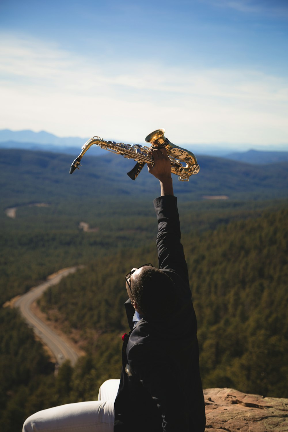 person holding up brass-colored saxophone