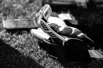 greyscale photo pair of gloves on grass field