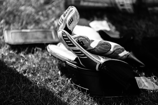 greyscale photo pair of gloves on grass field