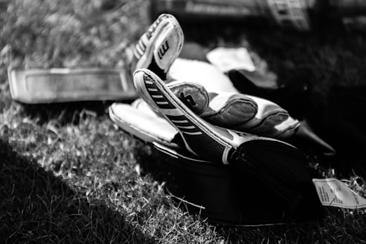 greyscale photo pair of gloves on grass field