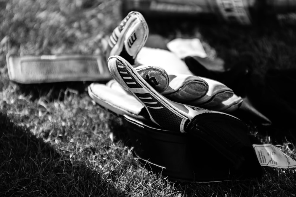 greyscale photo pair of gloves on grass field